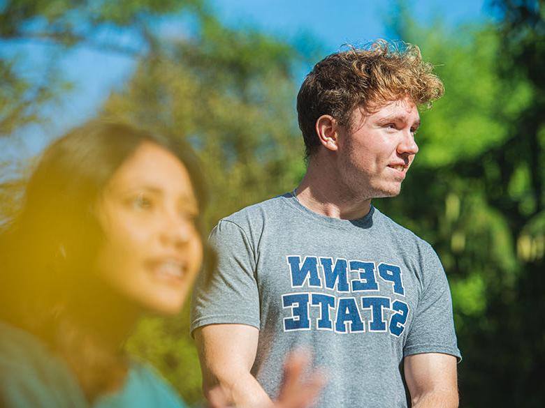 Students hang out on campus at Penn State 阿尔图纳, one wearing a Penn State shirt.
